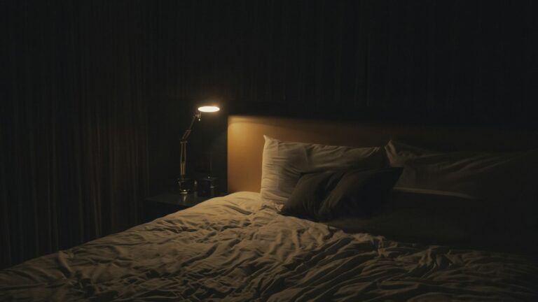 Bedside lamp glowing in a dark bedroom at night
